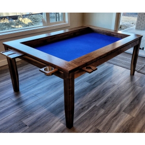 A table with a sunken middle surface for playing board games. sits in a living room with windows behind it, The table has cupholders and trays around the perimeter for holding drinks and game pieces